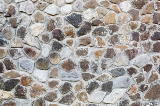 Large wall of natural stones of different size and colored gray texture on a summer day Background