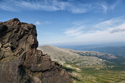 The man is high on the rock, against the background of the valley in clear weather. Conceptual design.