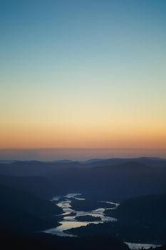 Summer landscape at sunset in the valley of the Siberian mountains. Silhouettes of peaks and rivers, in the rays of the departing sun