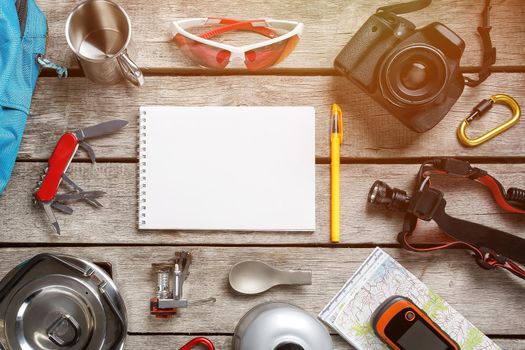 Top view of tourist equipment for travel and tourism on a rustic light wooden floor with an empty space in the middle. sunlight