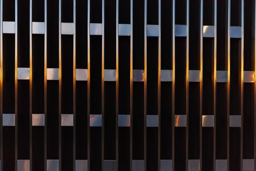 Abstract architectural detail of vertical lines with squares of metal at sunset. Wall texture