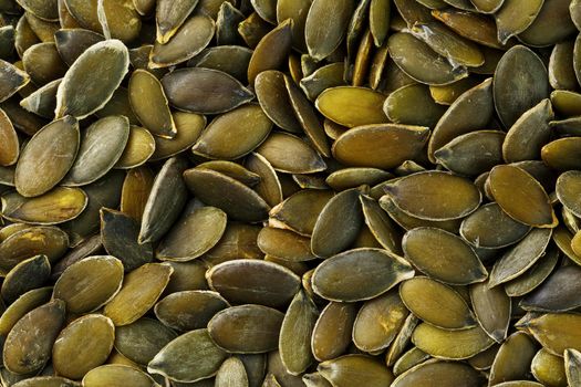 Macro background texture of green pumpkin seeds. Organic vegan food.