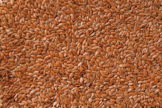 Background texture of seeds of dark brown flax. Grain on butter. Useful cereals.