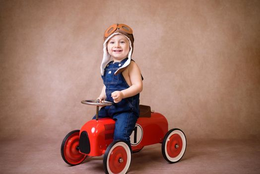 Child riding in red car. Kid holding Christmas bag. Xmas holiday concept.