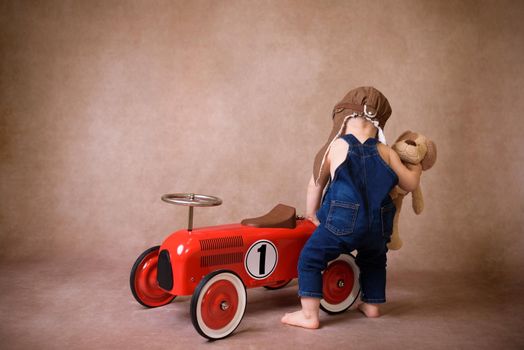 Child riding in red car. Kid holding Christmas bag. Xmas holiday concept