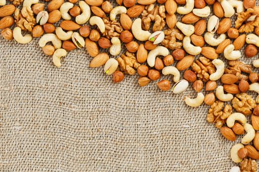 Roasted peanuts in their shells and peeled in a brown cup, against a gray wooden table. Organic vegetarian protein, macro.