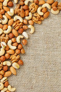 Roasted peanuts in their shells and peeled in a brown cup, against a gray wooden table. Organic vegetarian protein, macro.