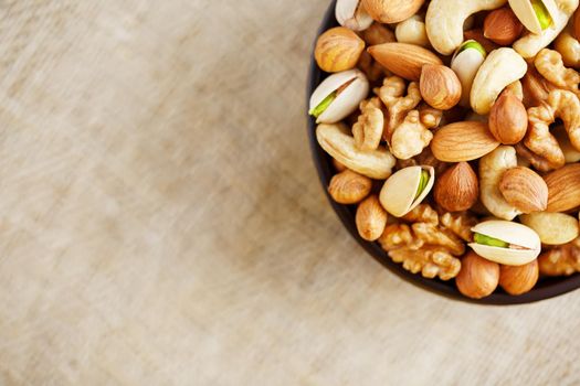 Mix of nuts of cashew, almonds, pistachios, hazelnuts and walnuts is against the background of brown fabric of burlap. Nuts as structure and background, macro