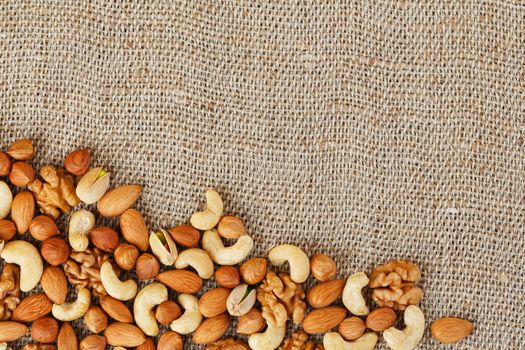 Roasted peanuts in their shells and peeled in a brown cup, against a gray wooden table. Organic vegetarian protein, macro.