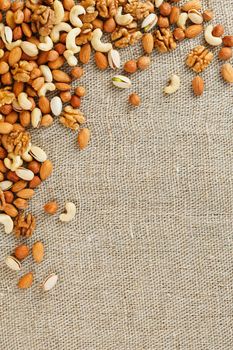 Roasted peanuts in their shells and peeled in a brown cup, against a gray wooden table. Organic vegetarian protein, macro.