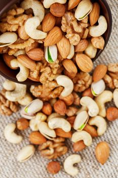 Wooden bowl with mixed nuts on a wooden gray background. Healthy food and snacks, organic vegetarian meals. Walnut, pistachios, almonds, hazelnuts and cashews, walnut.