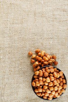 Peeled hazelnuts in a wooden, dark brown cup on a burlap cloth. Super Food, Raw. View from above.