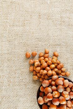 Peeled hazelnuts in a wooden, dark brown cup on a burlap cloth. Super Food, Raw. View from above.