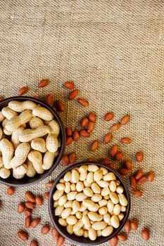 Peanuts in the shell and peeled closeup in a cup. Background with peanuts. Roasted peanuts in the shell and peeled on a background of brown cloth in cups