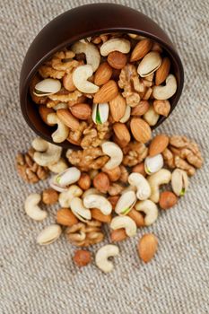 Wooden bowl with mixed nuts on a wooden gray background. Healthy food and snacks, organic vegetarian meals. Walnut, pistachios, almonds, hazelnuts and cashews, walnut.