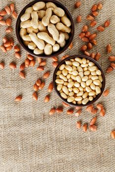 Peanuts in the shell and peeled closeup in a cup. Background with peanuts. Roasted peanuts in the shell and peeled on a background of brown cloth in cups