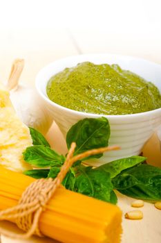 Italian traditional basil pesto pasta ingredients parmesan cheese pine nuts extra virgin olive oil garlic on a rustic table 