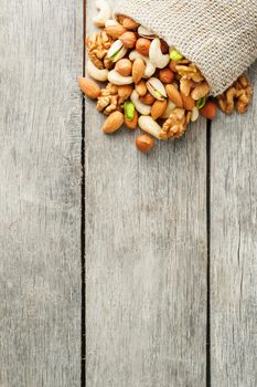 Mix of nuts of cashew, almonds, pistachios, hazelnuts and walnuts is against the background of brown fabric of burlap. Nuts as structure and background, macro