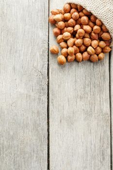 Chiselled hazelnuts in a bag of burlap on a gray wooden table. Organic Fresh Harvested. Without shell healthy vegetarian super food.