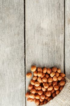 Chiselled hazelnuts in a bag of burlap on a gray wooden table. Organic Fresh Harvested. Without shell healthy vegetarian super food.