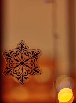 Golden bokeh on orange background with snowflake. Glittering lights are not in sharpness. defocus