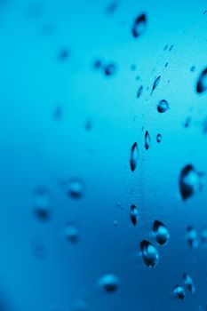 Drops of clean water on the glass. Blue background.