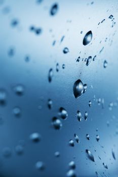 Drops of clean water on the glass. Blue background.