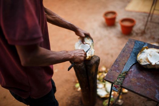 Opening green fresh coconut with big knife.