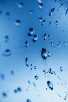 Drops of clean water on the glass. Blue background.