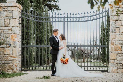 Happy stylish smiling couple walking in Tuscany, Italy on their wedding day. The bride and groom walk down the street by the hands. A stylish young couple walks. Husband and wife communicate nicely. Lovers run through the streets of the city.