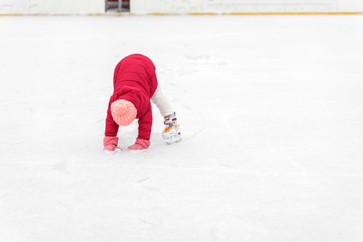 cute little girl in a hat with a bumbon on ice skates on a winter day