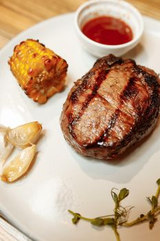 BBQ Grilled rib eye steak, fried rib-eye beef meat on a plate with green salad. Dark background.