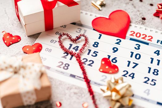 Flat lay of Valentines day calendar composition. Top view Gifts, paper, hearts confetti, ribbon on grey table background. 14th February love concept.