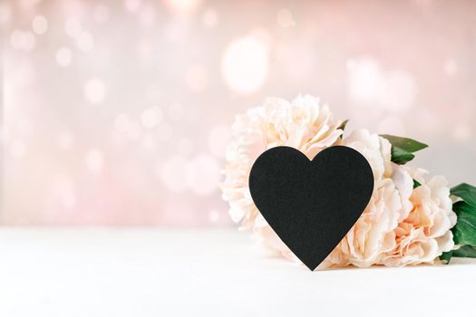 Still life Valentines day festive background with empty black chalkboard heart on white table background. Mockup with copy space for design.