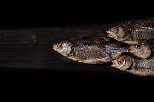 Dried or jerky salted taranka, tasty clipfish on wooden background. Beer snack. Traditional way of preserving fish. Close up, top view