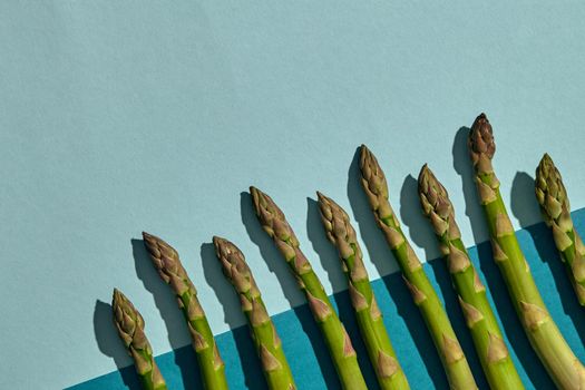 Some ripe raw asparagus stalks on colorful background. Concept of healthy food and crop of spring vegetables. Close up, copy space. Flat lay, top view