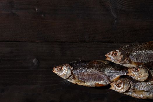 Jerky or dried salted roach, delicious clipfish on wooden background. Popular beer snack. Traditional way of preserving fish. Close up, top view