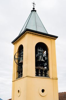 Yellow bell tower spire with vintage black bells. High quality photo