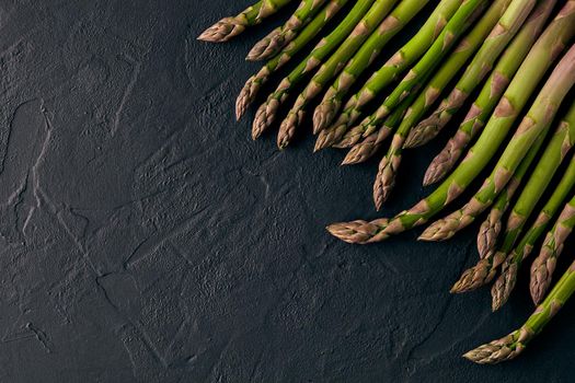 Asparagus stems against black slate background. Concept of healthy nutrition, food and seasonal vegetables harvest. Close up, copy space. Flat lay, top view