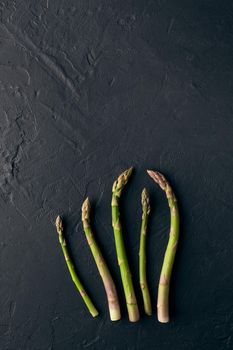 Fresh green organic asparagus spears on black slate background. Concept of healthy nutrition, food and seasonal vegetables harvest. Close up, copy space. Flat lay, top view