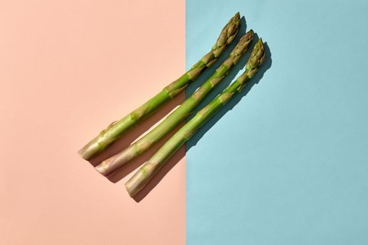 Three green asparagus spears on colorful background. Concept of healthy nutrition, food and seasonal vegetables harvest. Close up, copy space. Flat lay, top view