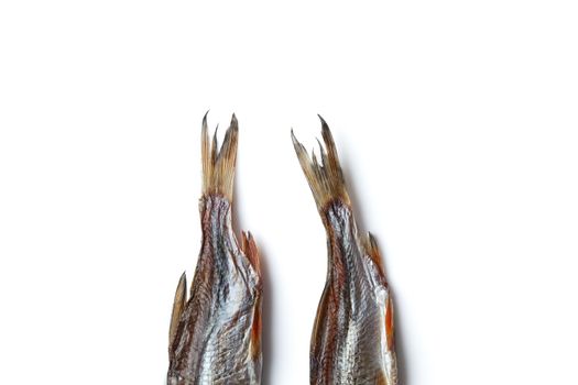 Two jerky or dried salted taranka tails, tasty clipfish isolated on white background. Popular beer snack. Traditional way of preserving fish. Close up, copy space, top view