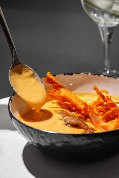 Close-up shot of a delicious cream soup with meat served on a black table with a glass of wine, top view. Gourmet meal, restaurant serving. Cooking concept.
