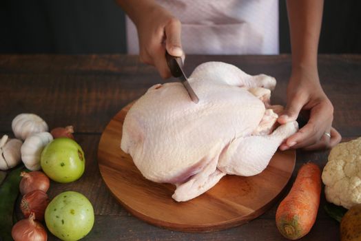 raw whole chicken on wooden background .