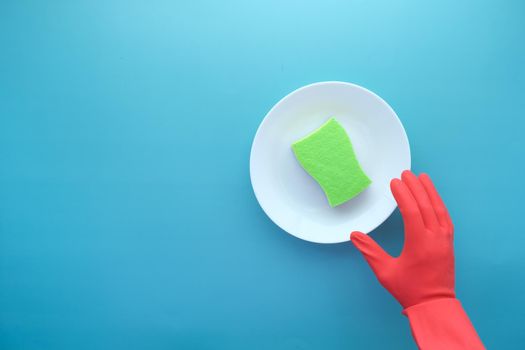 sponge , rubber gloves and colorful plate on blue .