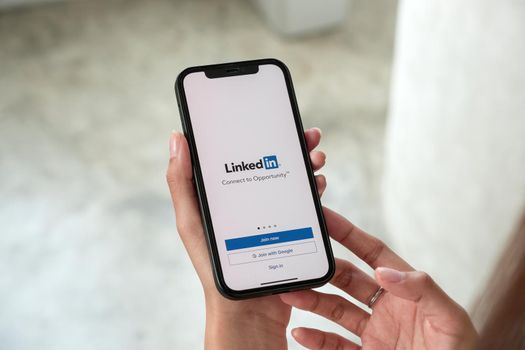 CHIANG MAI, THAILAND, JAN 15, 2022 : A women holds Apple iPhone 13 Pro max with LinkedIn application on the screen.LinkedIn is a photo-sharing app for smartphones.