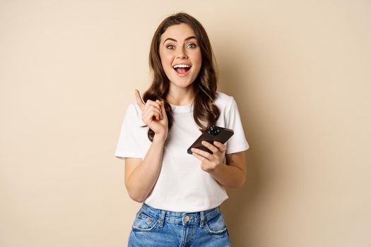 Enthusiastic woman holding smartphone and laughing, found smth online, concept of shopping and cellular technology.