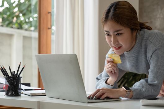 Close up image of a happy woman holding credit card while using laptop computer. online shopping with cash back, discount sales, low prices, saving money. Money back concept