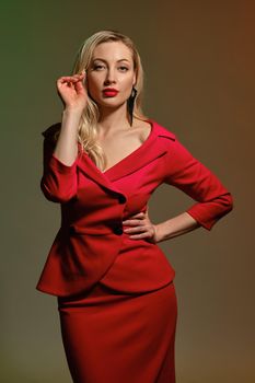 Blonde lady, bright make-up, in red dress and black earrings. Holding something, hand on waist, posing on colorful background. Template, mockup for your advertising and design. Copy space, close up