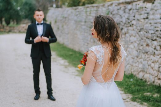 Happy stylish smiling couple walking in Tuscany, Italy on their wedding day. The bride and groom walk down the street by the hands. A stylish young couple walks. Husband and wife communicate nicely. Lovers run through the streets of the city.